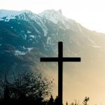 brown cross on brown tree near snow covered mountain during daytime