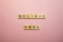 A Believe and Pray Words of Encouragement on Pink Surface