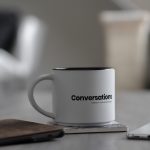 white conversations printed mug near smartphone