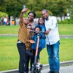 man in white dress shirt and blue denim jeans holding orange and black kick scooter