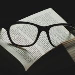 black framed eyeglasses on top of open book