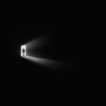 a person standing in a doorway with a light coming through it