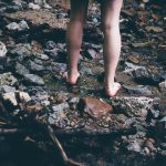 woman standing on rocks with water flowing