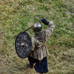 person in brown jacket holding black round metal