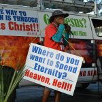 A street preacher delivers a message about salvation and eternity with a bold van poster.