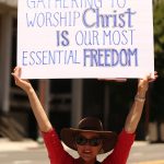 Woman holds a Christian freedom sign in Los Angeles street protest.