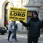 man in blue jacket holding blue and white signage