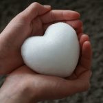 a person holding a white heart in their hands