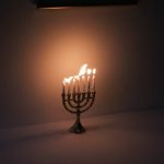 A glowing menorah illuminates a dark room, symbolizing the festival of Hanukkah.