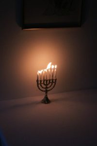 A glowing menorah illuminates a dark room, symbolizing the festival of Hanukkah.
