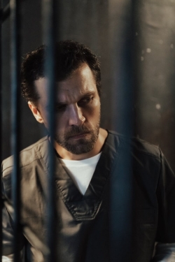 Portrait of a serious man with facial hair in a prison cell, emphasizing incarceration themes.