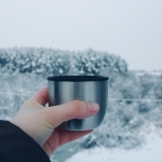 a person holding a cup in front of a snowy landscape
